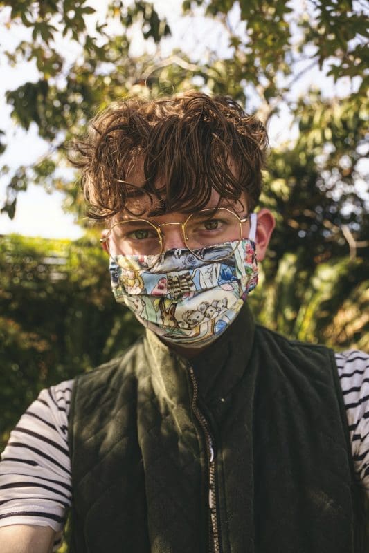 boy in green and black camouflage jacket wearing white mask