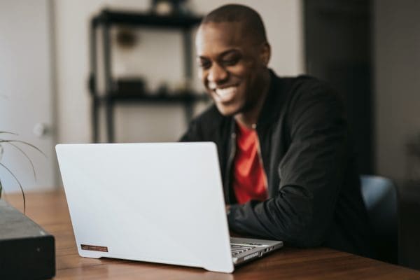 man in black blazer sitting by the table with macbook